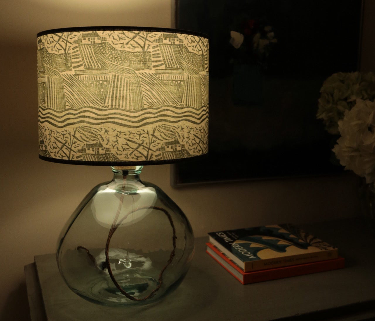 Decorative lamp with a patterned shade in a dimly lit room.