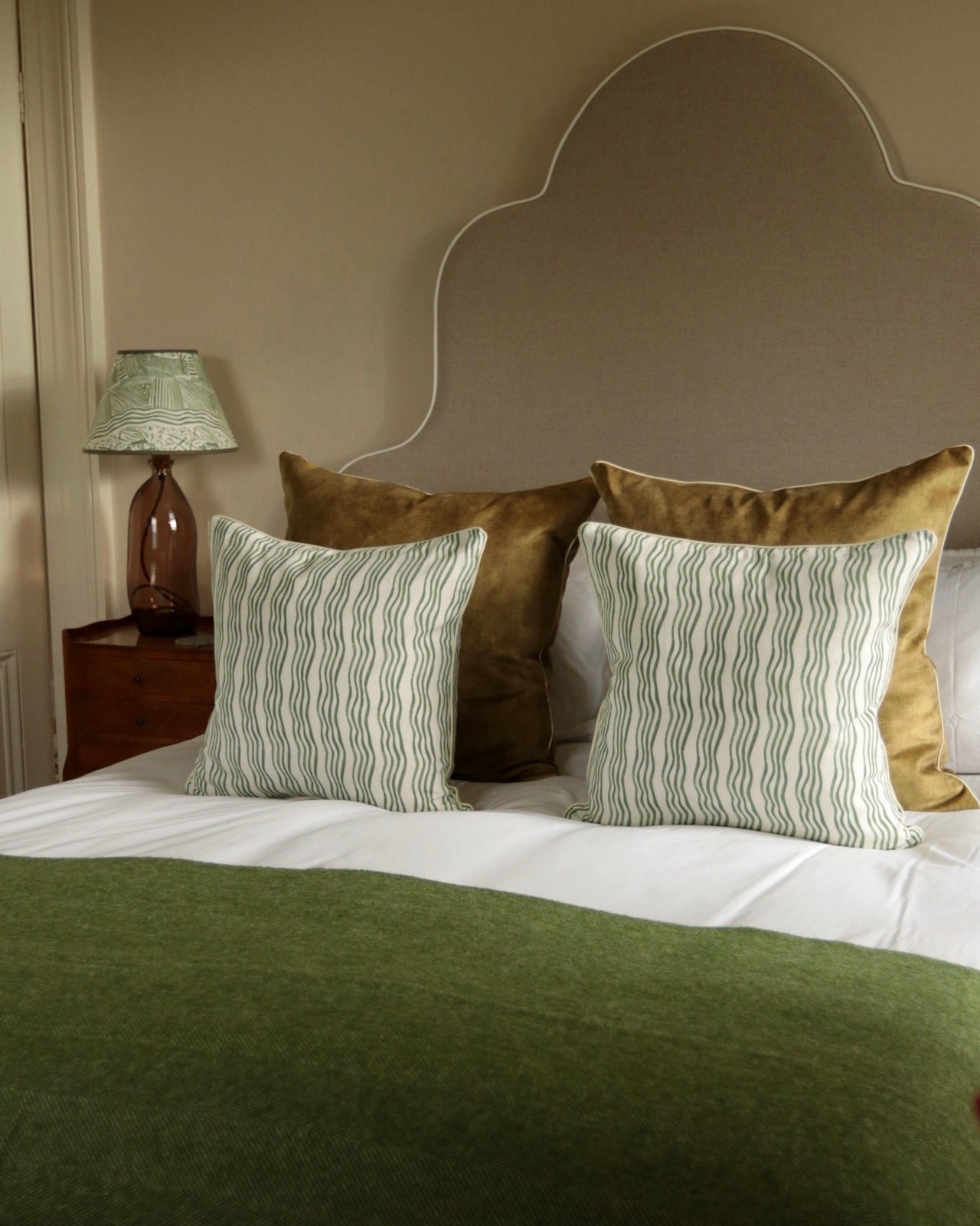 Green striped cushions on a bed with a green throw.