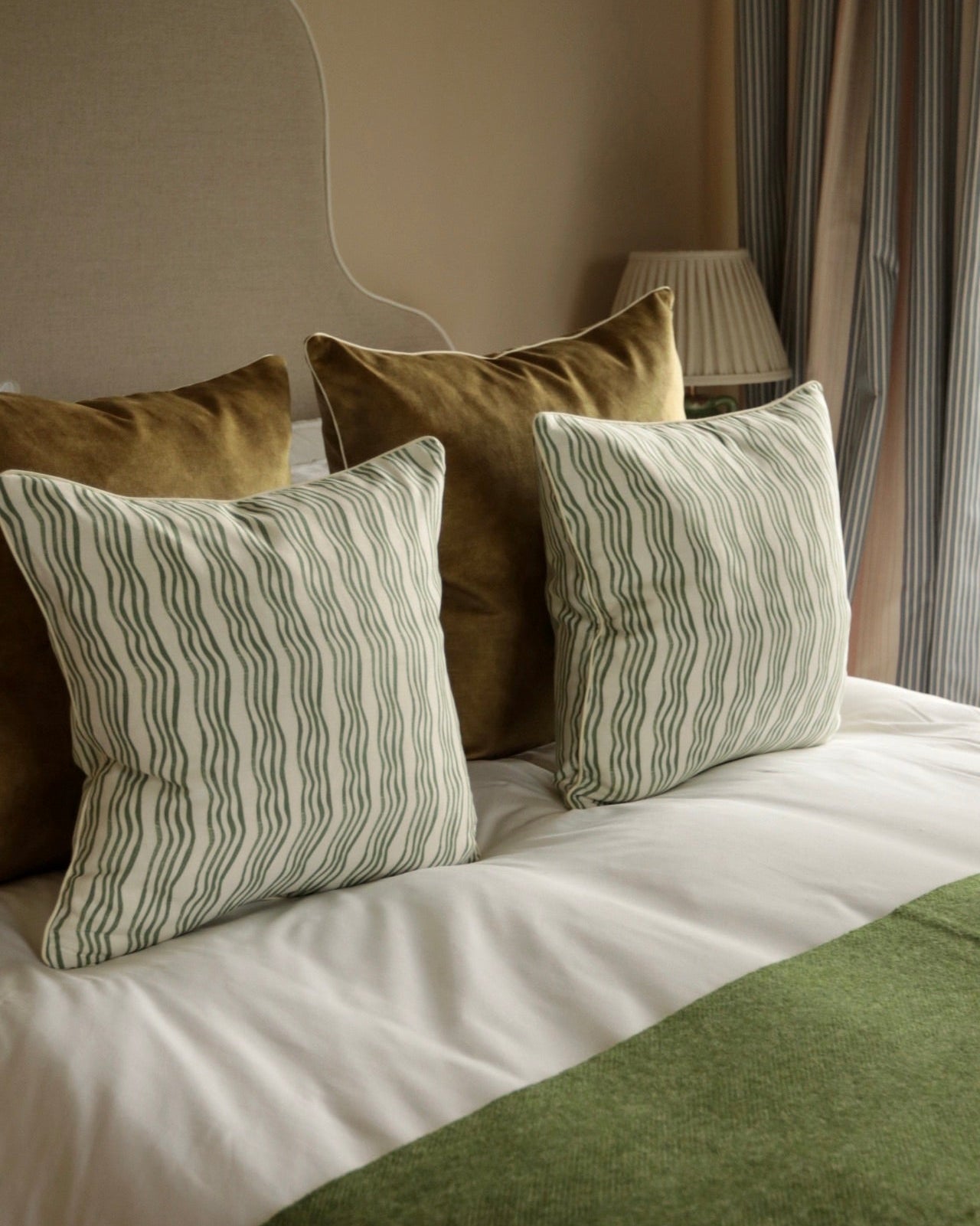 Green stripe cushions on a bed with a green throw.