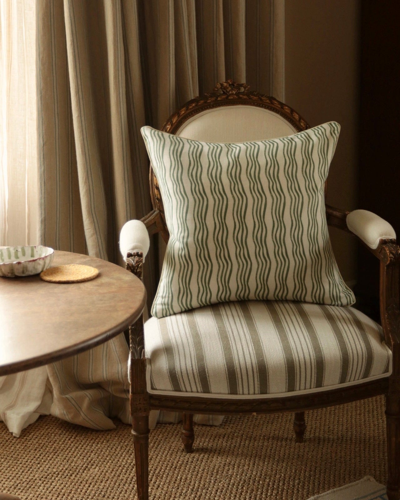 Chair with a striped cushion in a room with curtains and a side table.